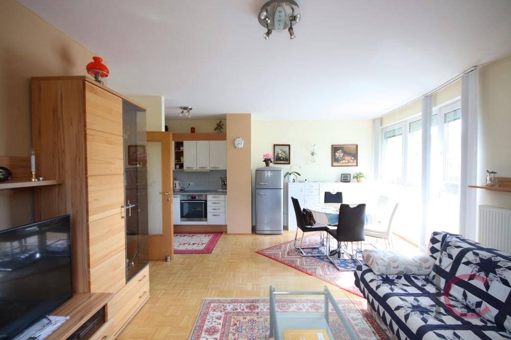 Heller offener Wohn- und Essbereich mit Parkettboden und integrierter Küchenzeile.