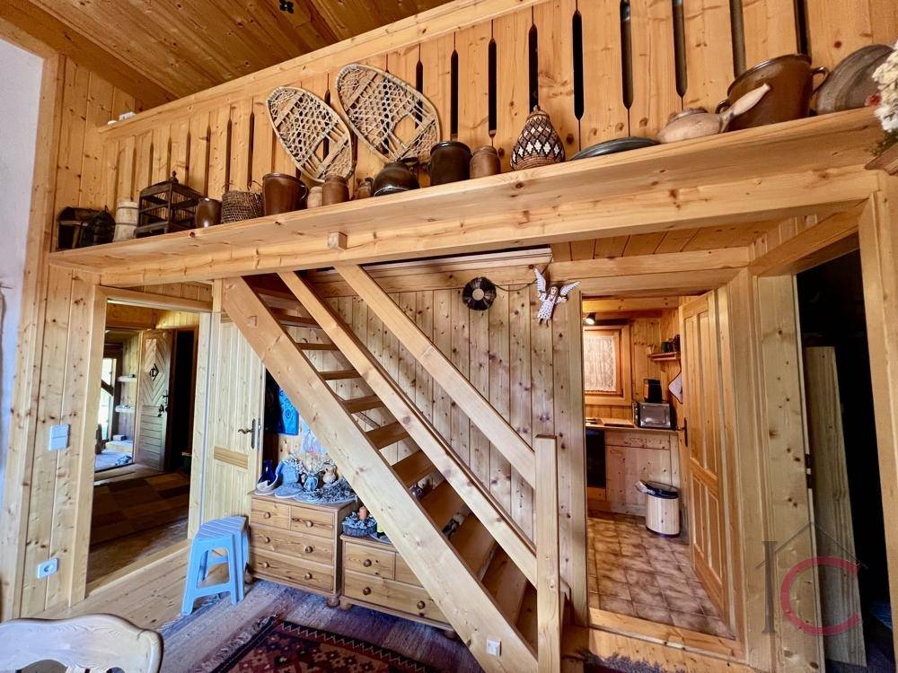 Innenansicht mit Holztreppe, die zu einem oberen Bereich führt, und Blick in die Küche.