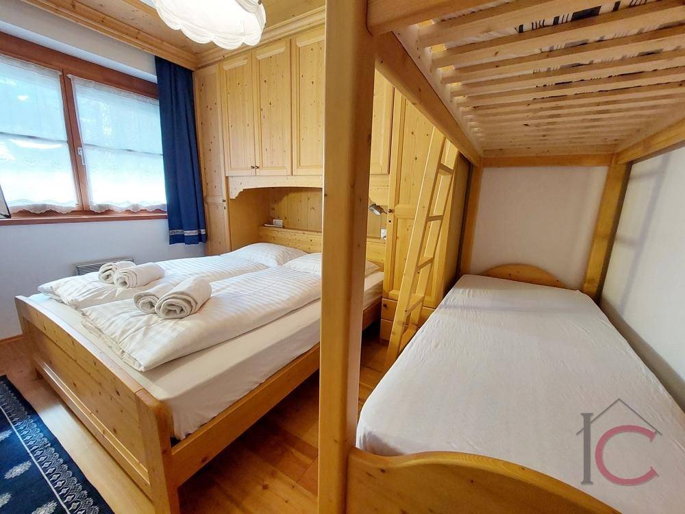 Gemütliches Schlafzimmer mit Holzbett, Etagenbett und traditionellen Holzschränken.