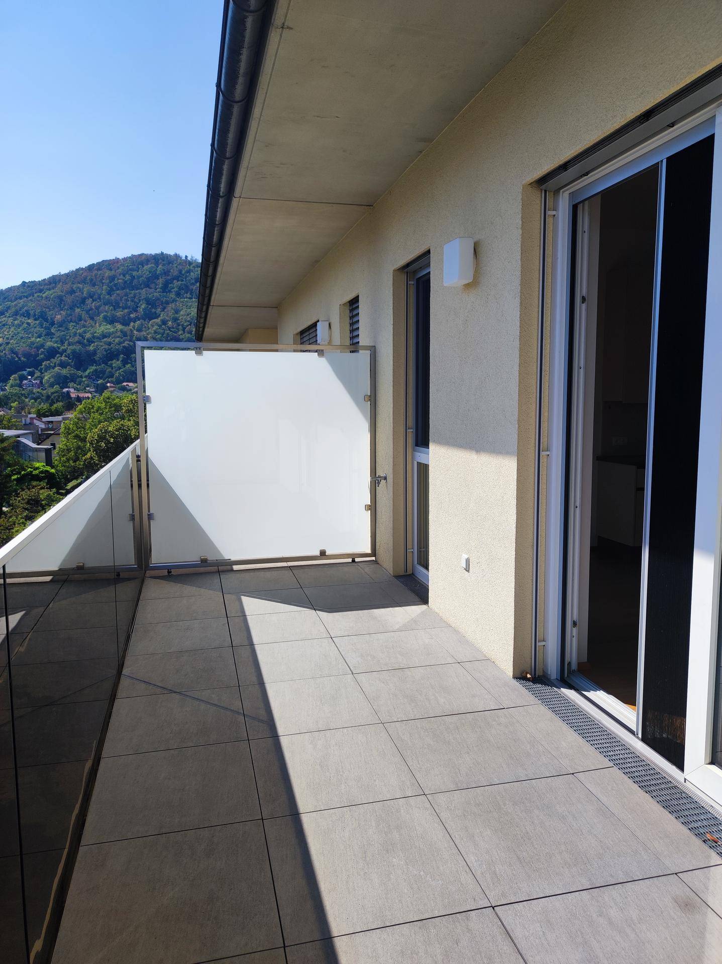 Geräumige Dachterrasse mit Fliesenboden und Glasbrüstung, ideal für Entspannung im Freien.