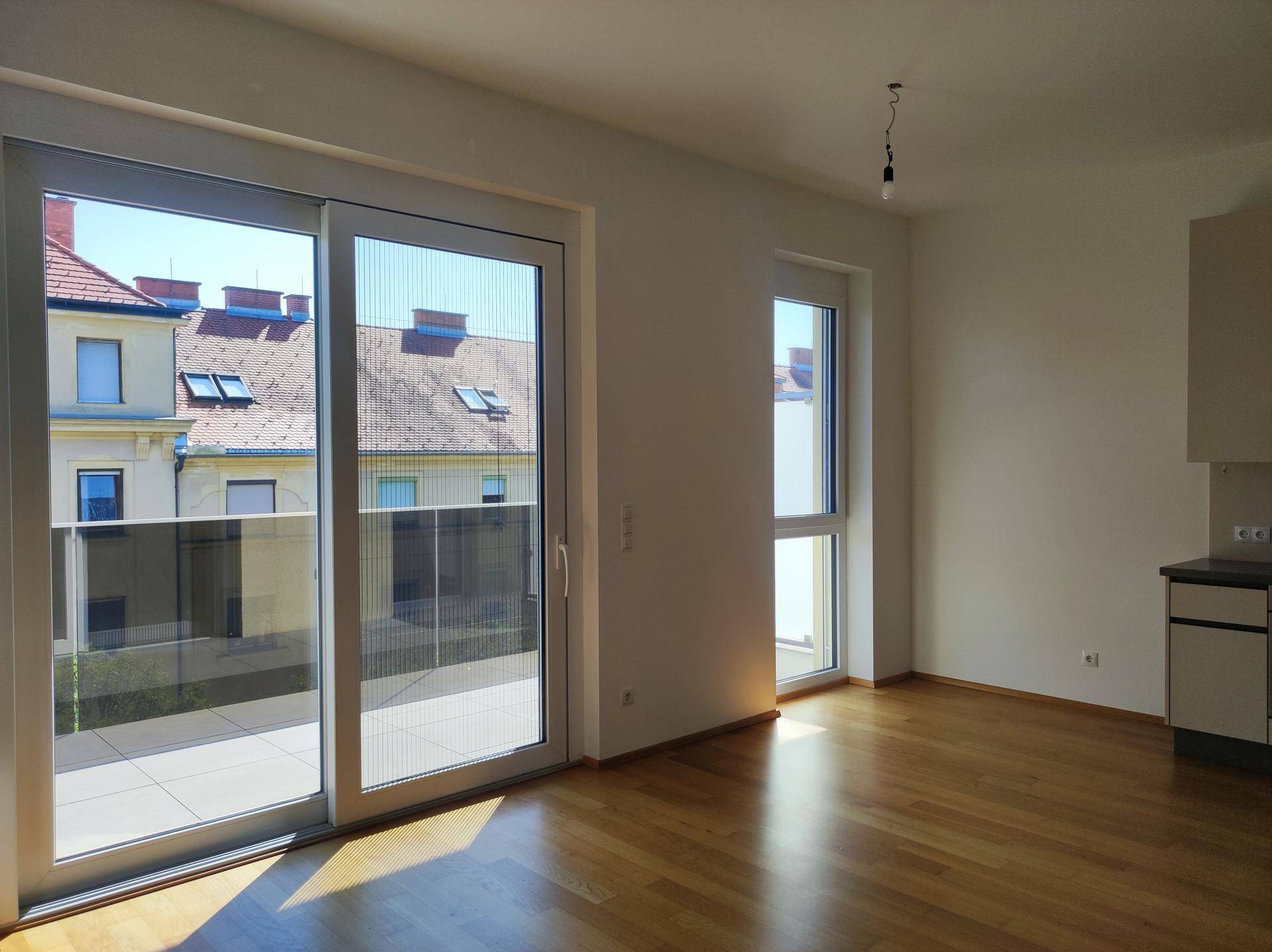 Lichtdurchfluteter Wohnbereich mit Holzboden und direktem Zugang zu einer großen Terrasse.