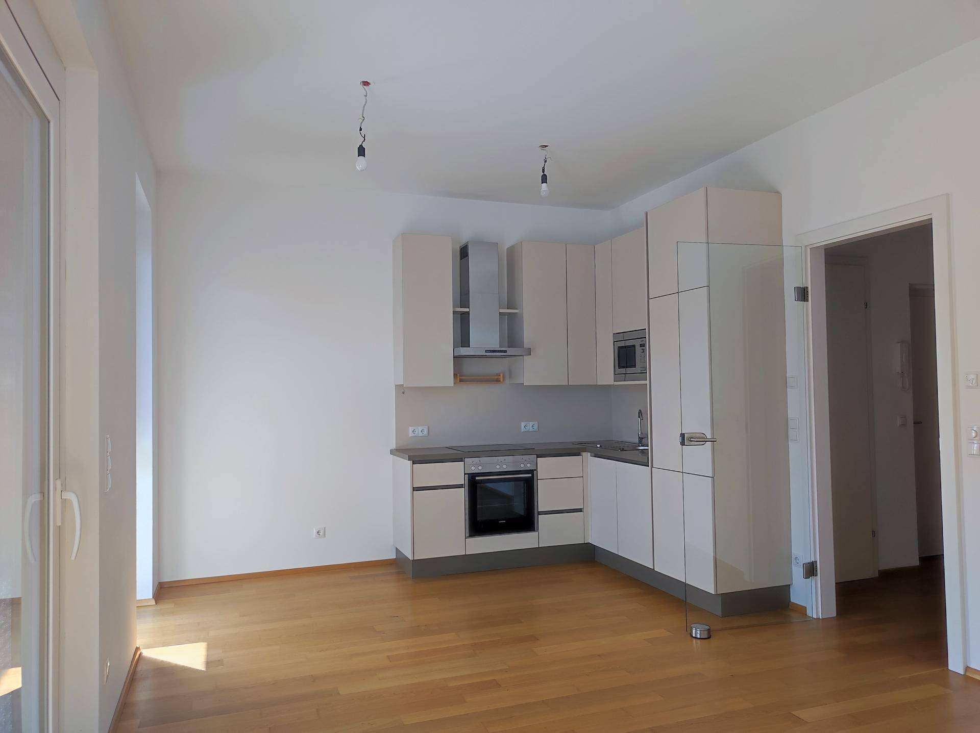 Heller offener Wohnbereich mit integrierter Küche und Zugang zur Terrasse.
