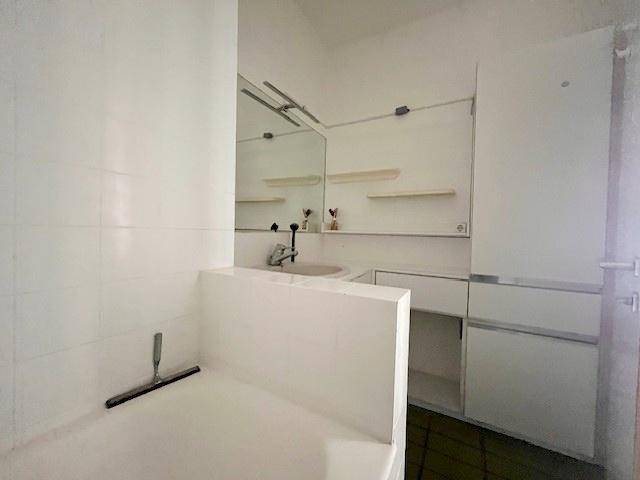 Badezimmer mit Waschbecken, Spiegel und weiß gefliesten Wänden.