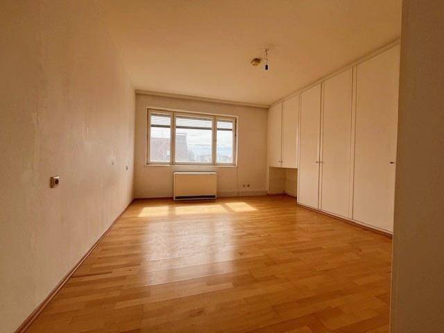 Schlafzimmer mit Parkettboden, Fenster und integrierten Wandschränken.