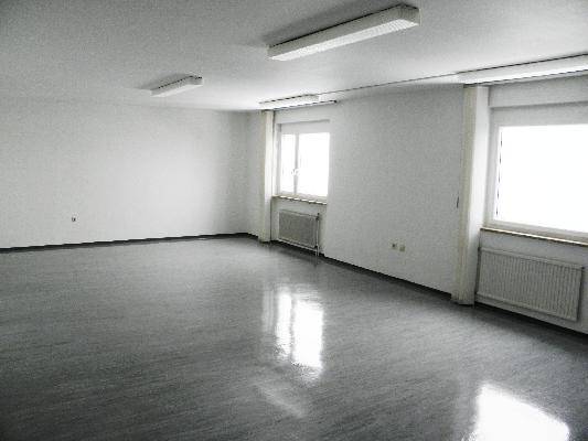 Helles Büro mit zwei Fenstern und Heizkörpern, bietet viel Platz für Arbeitsbereiche.