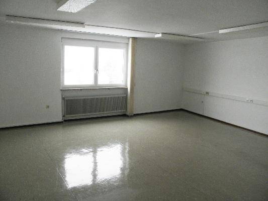 Geräumiges, leeres Büro mit großem Fenster und Heizkörper, bereit zur individuellen Einrichtung.
