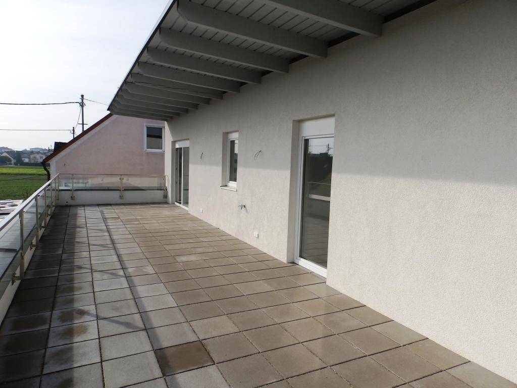 Lange Terrasse mit Fliesenboden und Blick auf die grüne Landschaft, bietet viel Ruhe.