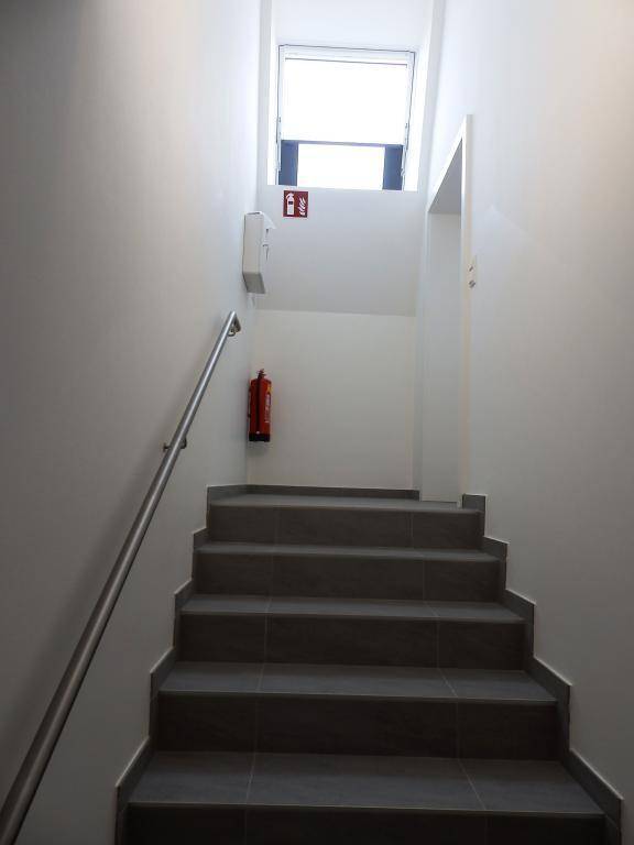 Treppenhaus mit Fliesenstufen, Handlauf und Brandschutzvorrichtung, sicher und funktional.