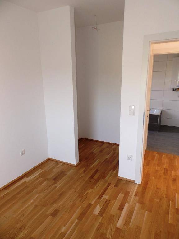 Heller Raum mit Parkettboden und offenem Zugang zu einem gefliesten Bereich.