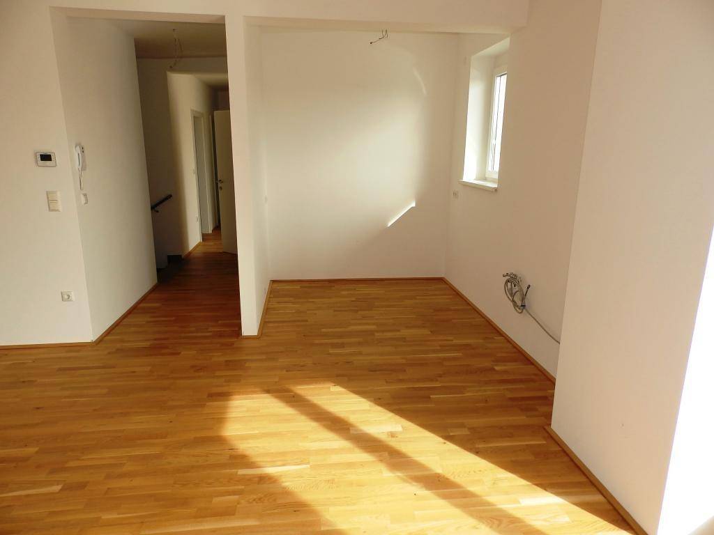 Offener Wohnbereich mit Parkettboden und Blick in den Flur, lichtdurchflutet.