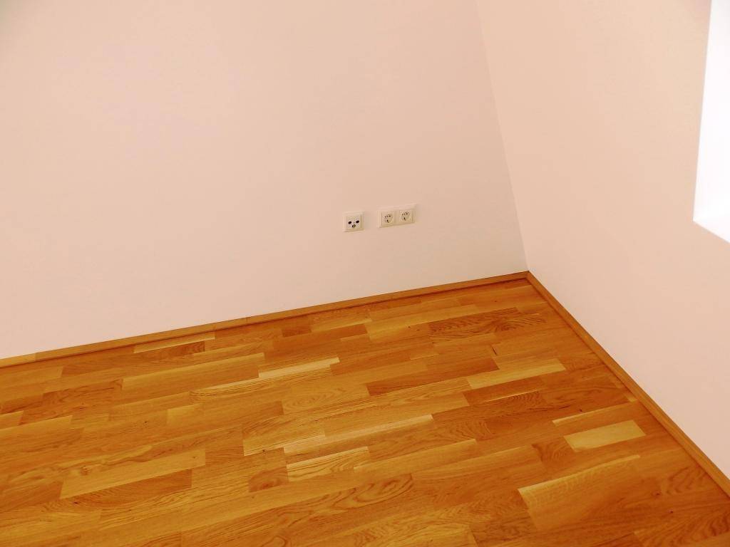 Detailansicht einer Wand mit Steckdosen und Fußleiste, in neuwertigem Zustand.