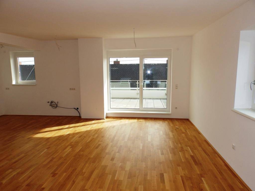 Heller Wohnbereich mit großem Terrassenzugang und Parkettboden, ideal für geselliges Beisammensein.
