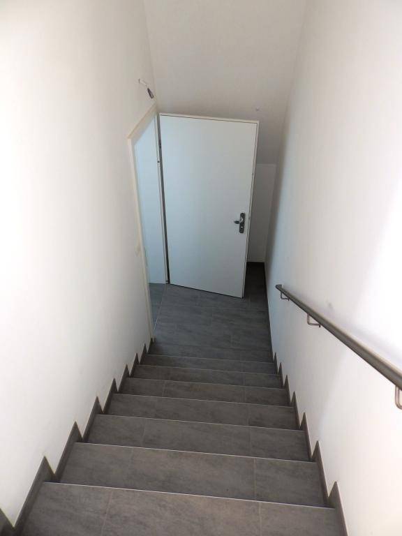 Blick von oben auf den Treppenabgang mit Fliesenstufen und Handlauf.