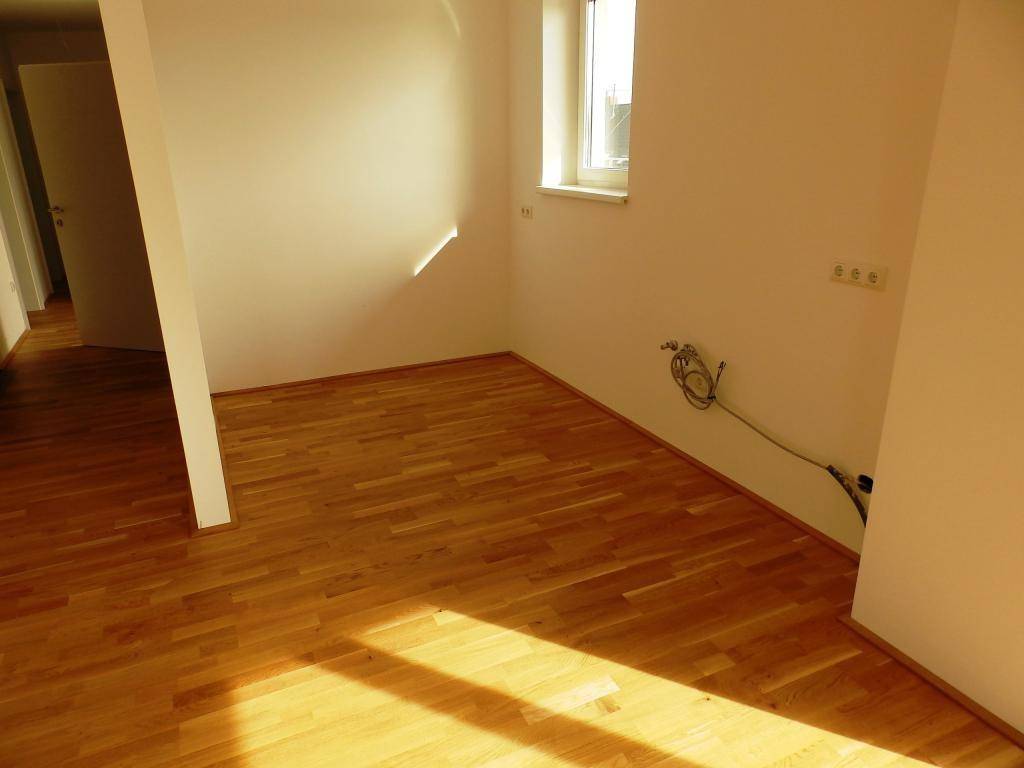 Helle Ecke eines Zimmers mit Parkettboden und Fenster, bereit zur individuellen Einrichtung.