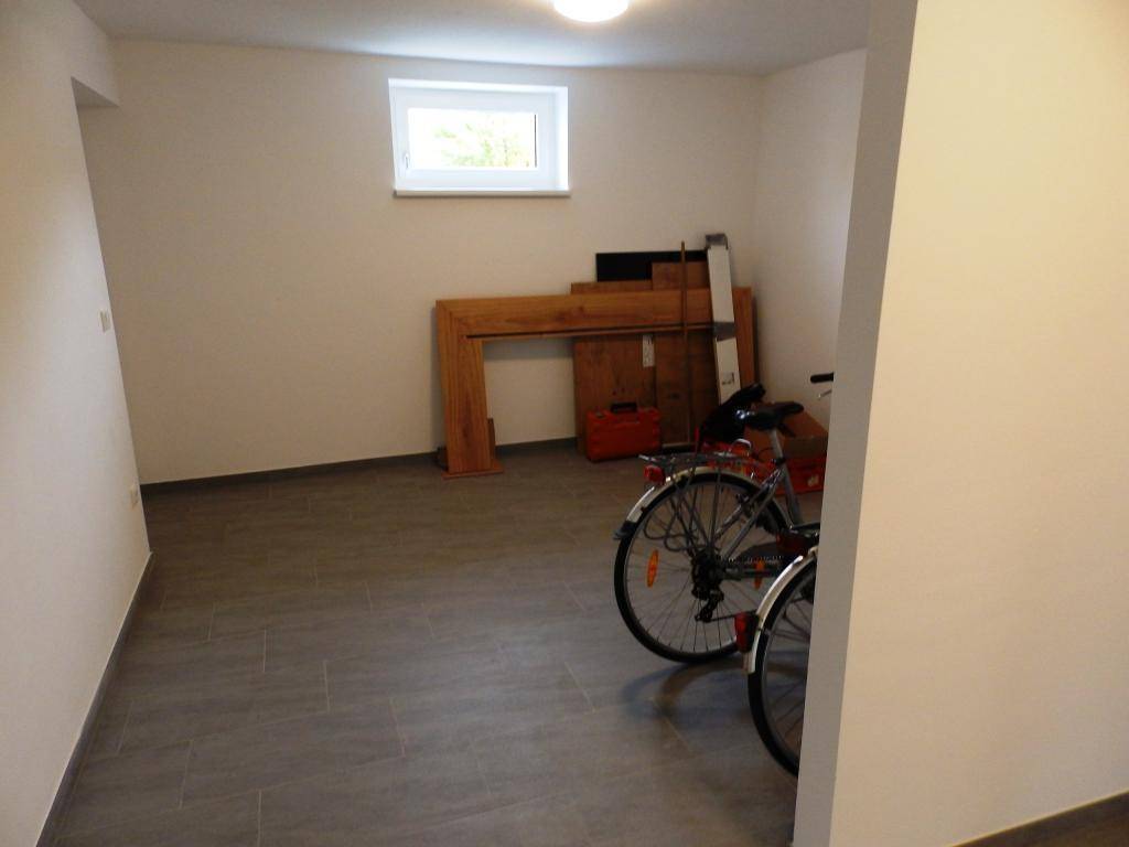 Geräumiger Kellerraum mit Fenster und Fliesenboden, bietet Stauraum und Platz für Fahrräder.