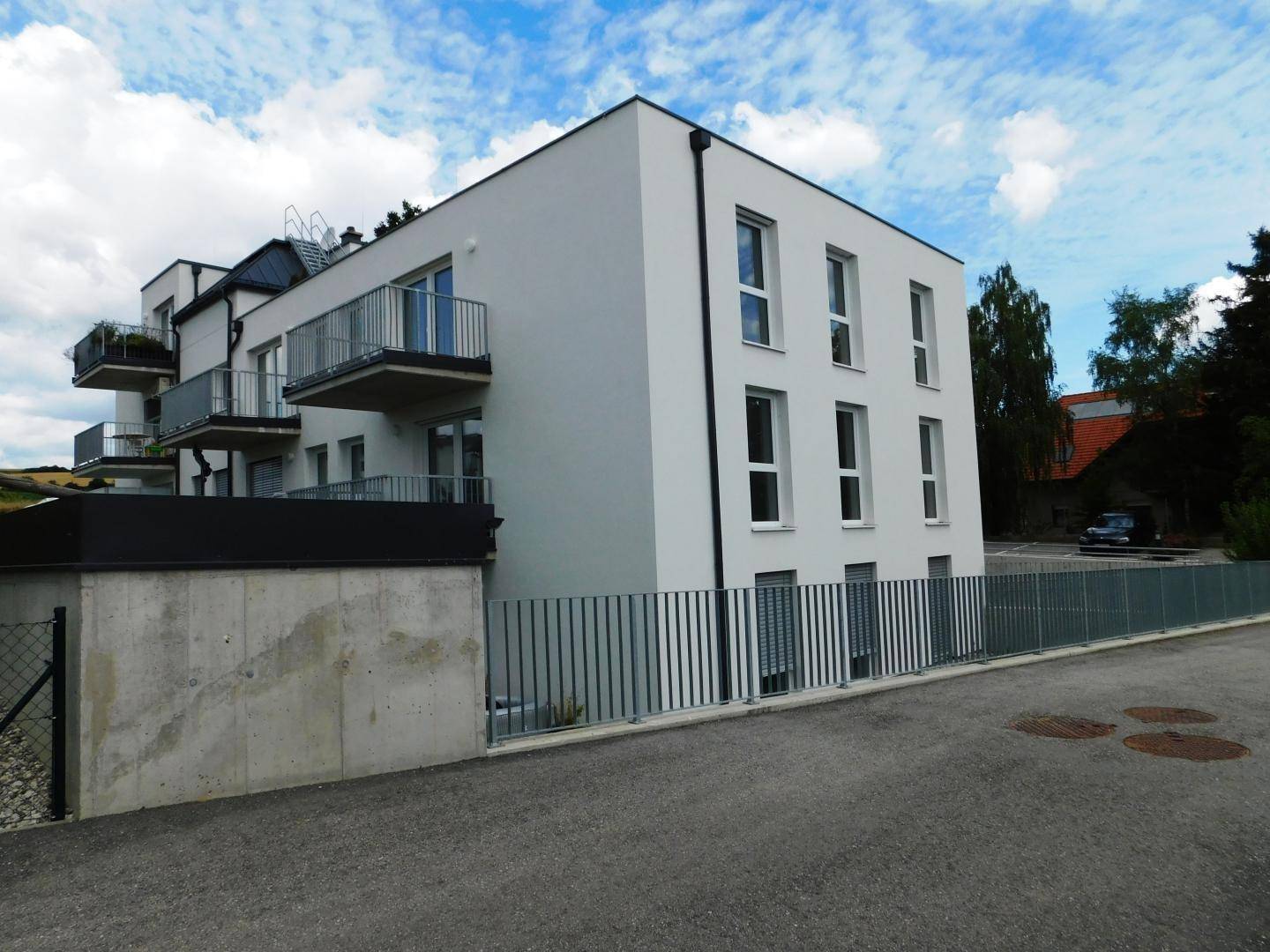 Modernes Mehrfamilienhaus mit klaren Linien, Balkonen und einer schlichten, hellen Fassade.