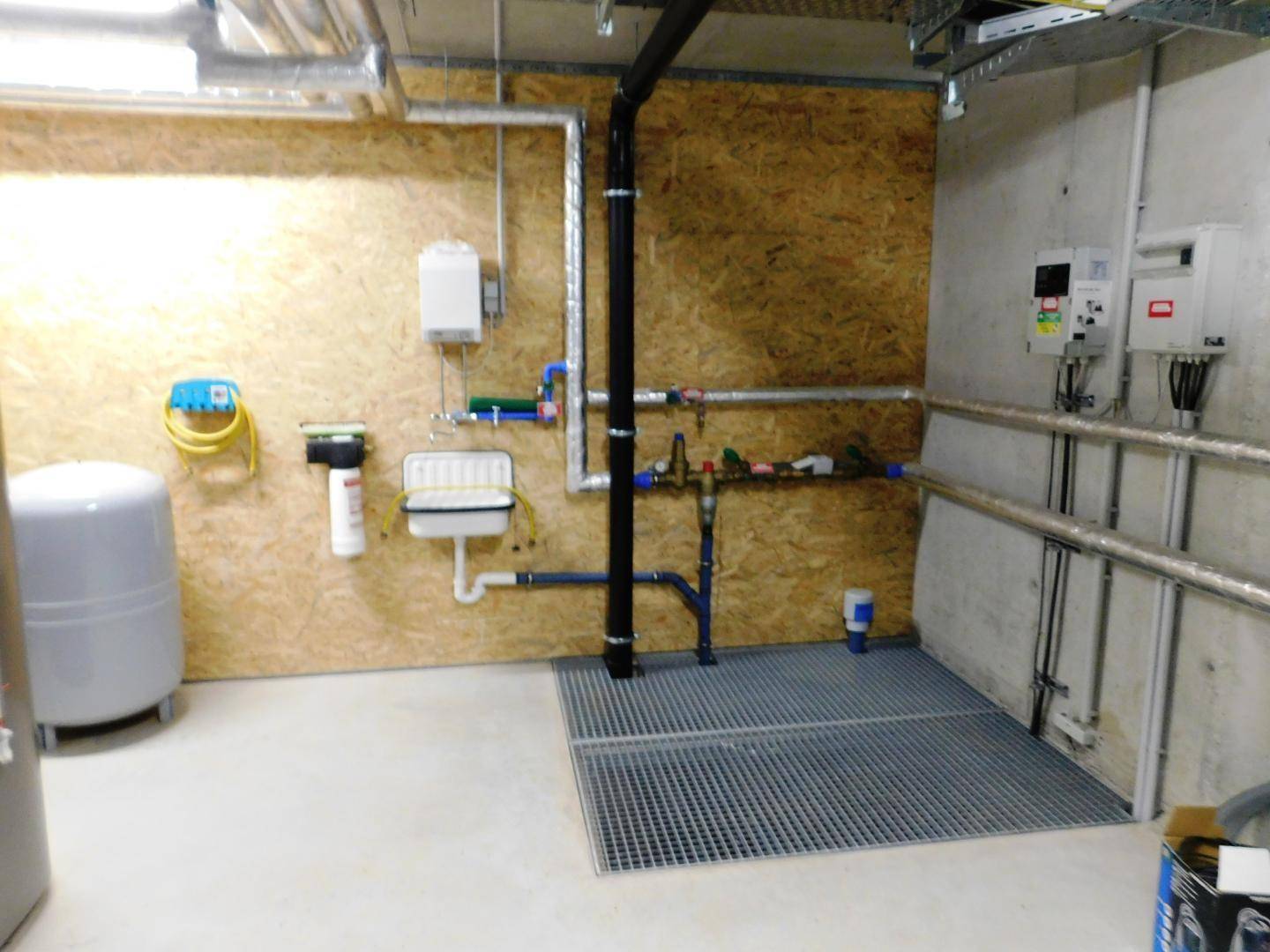 Technischer Raum mit Wasserinstallationen, Zählern und einem kleinen Waschbecken für Wartungsarbeiten.
