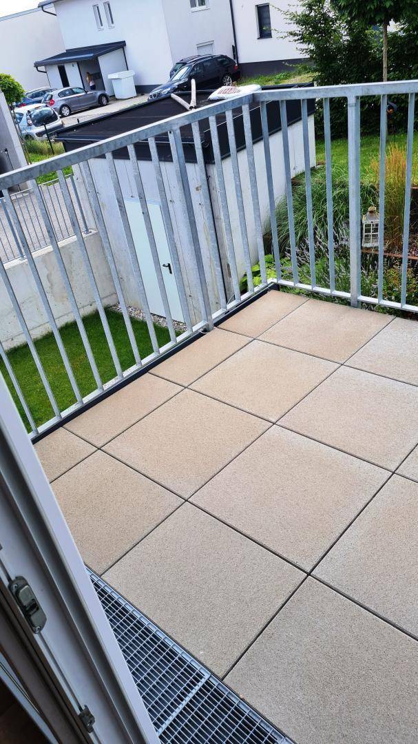 Geräumiger Balkon mit Fliesenboden und einem stabilen Metallgeländer, ideal für Entspannung.