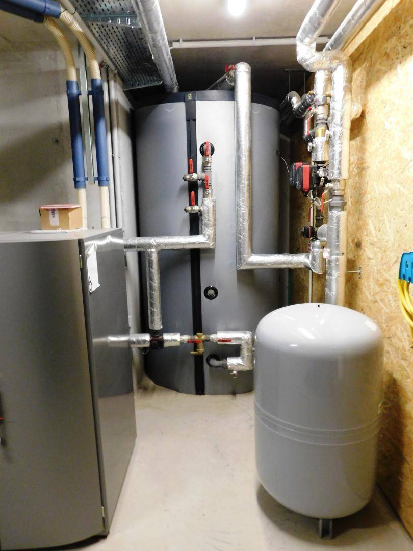 Große Warmwasserspeicher und Rohrleitungen in einem technischen Versorgungsraum des Gebäudes.
