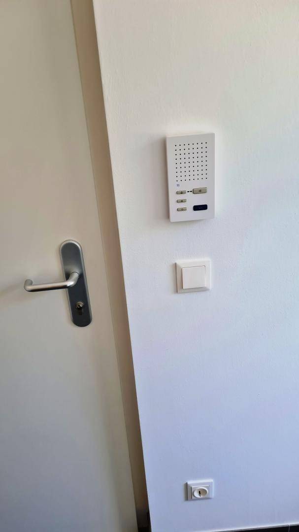 Nahaufnahme einer Gegensprechanlage und eines Lichtschalters an einer weißen Wand.