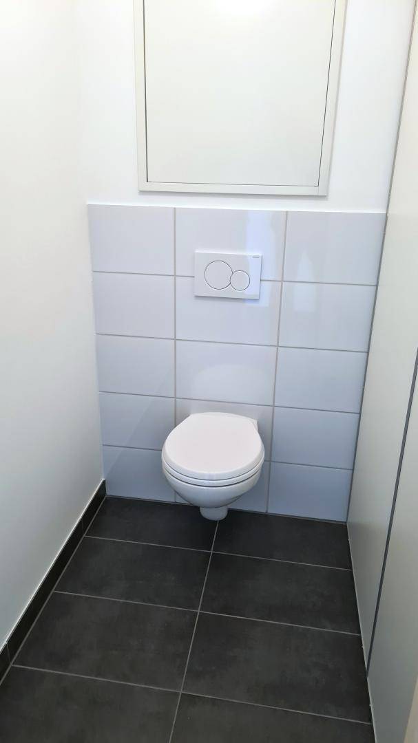 Gäste-WC mit Wand-WC und weißen Fliesen, in einem modernen und gepflegten Zustand.