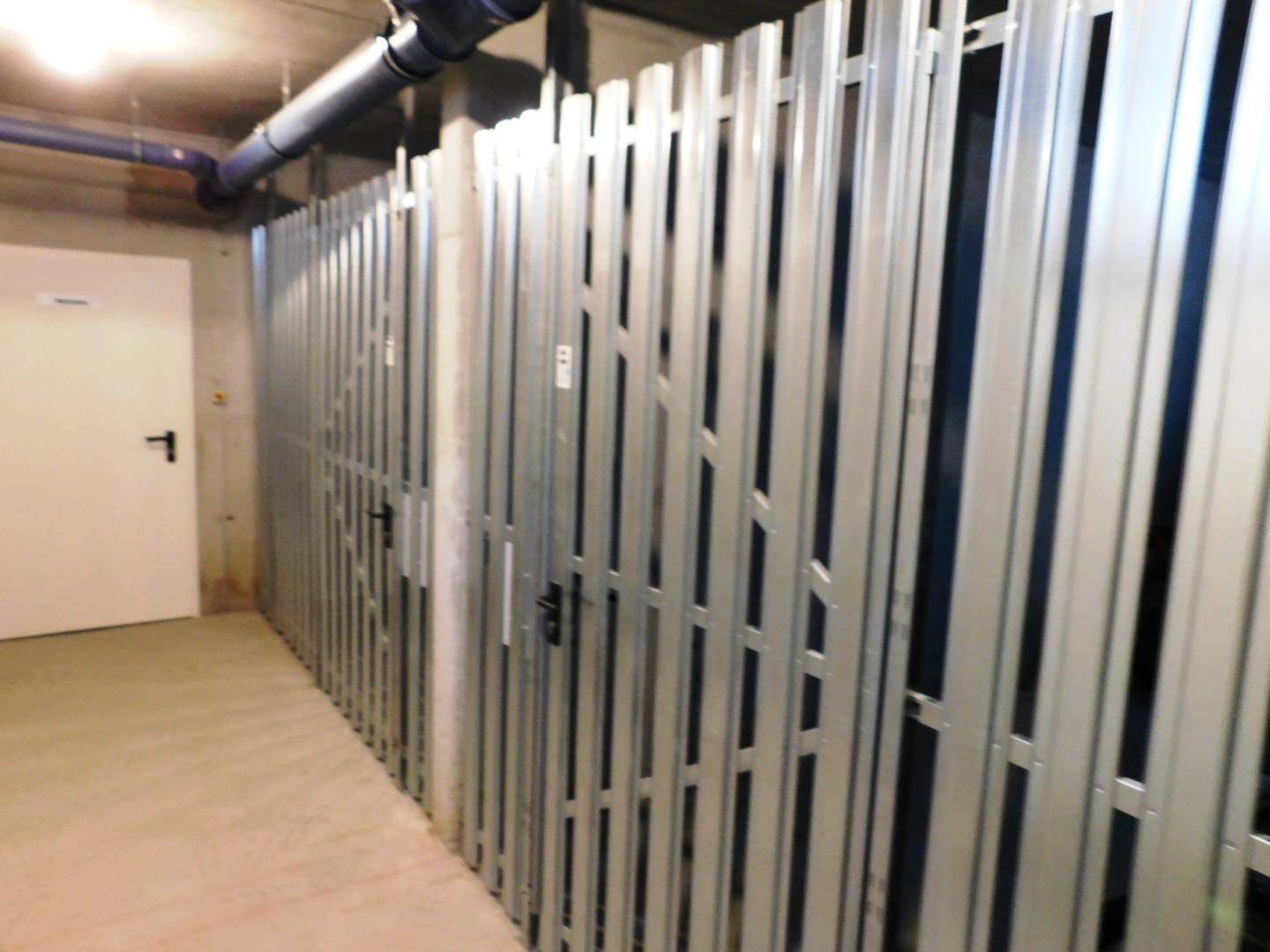 Abgetrennte Lagerabteile mit Metallgittern in einem Kellerbereich des Gebäudes für Bewohner.