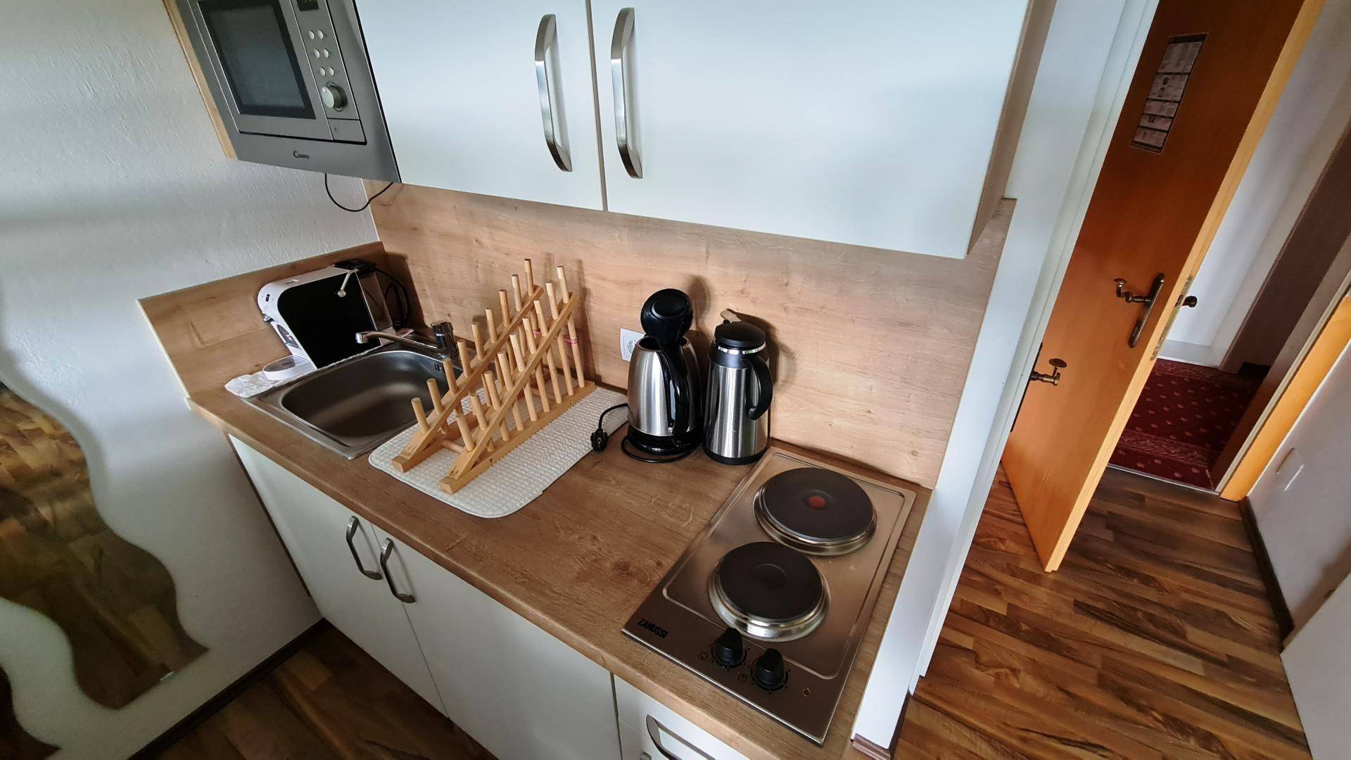 Detailansicht der Küchenzeile mit Spüle, Kochplatten und Mikrowelle, ideal für kleine Mahlzeiten.