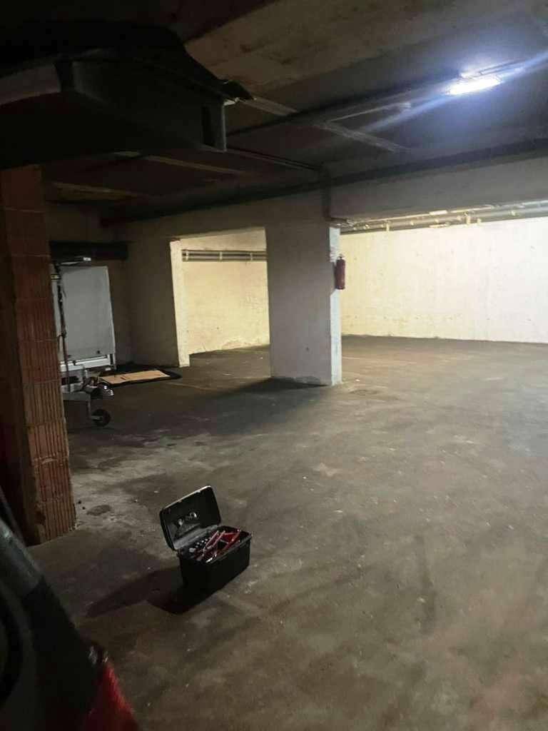 Weitläufige Tiefgarage oder Lagerhalle mit Betonstützen und einfacher Beleuchtung.