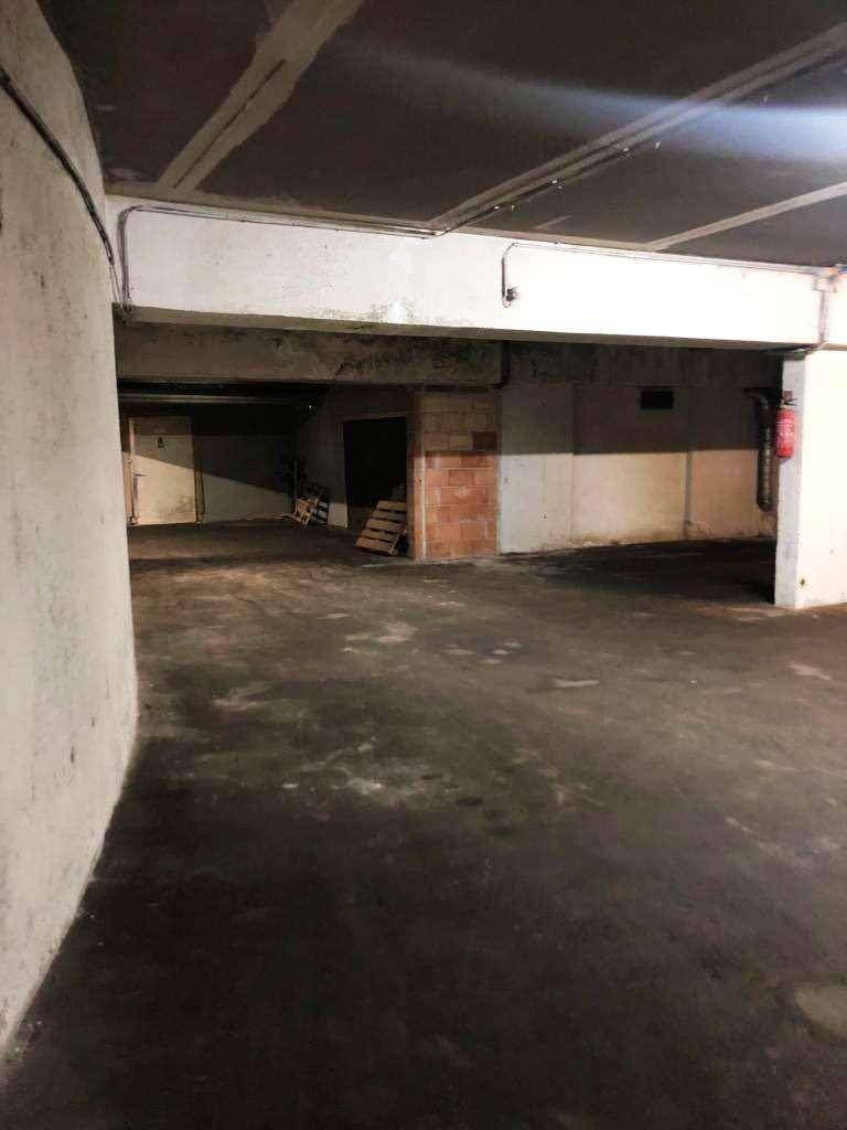 Weitläufiger Garagenbereich im Untergeschoss mit sichtbaren Betonstrukturen und Beleuchtung.