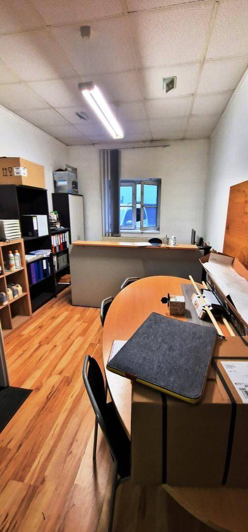 Funktionales Büro mit Holzfußboden, einem großen Schreibtisch und Regalen voller Aktenordner.