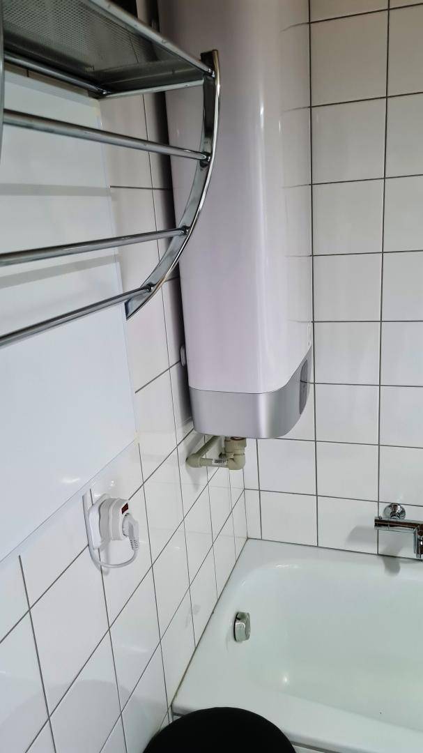 Badezimmer mit Badewanne, Handtuchhalter und weiß gefliesten Wänden.