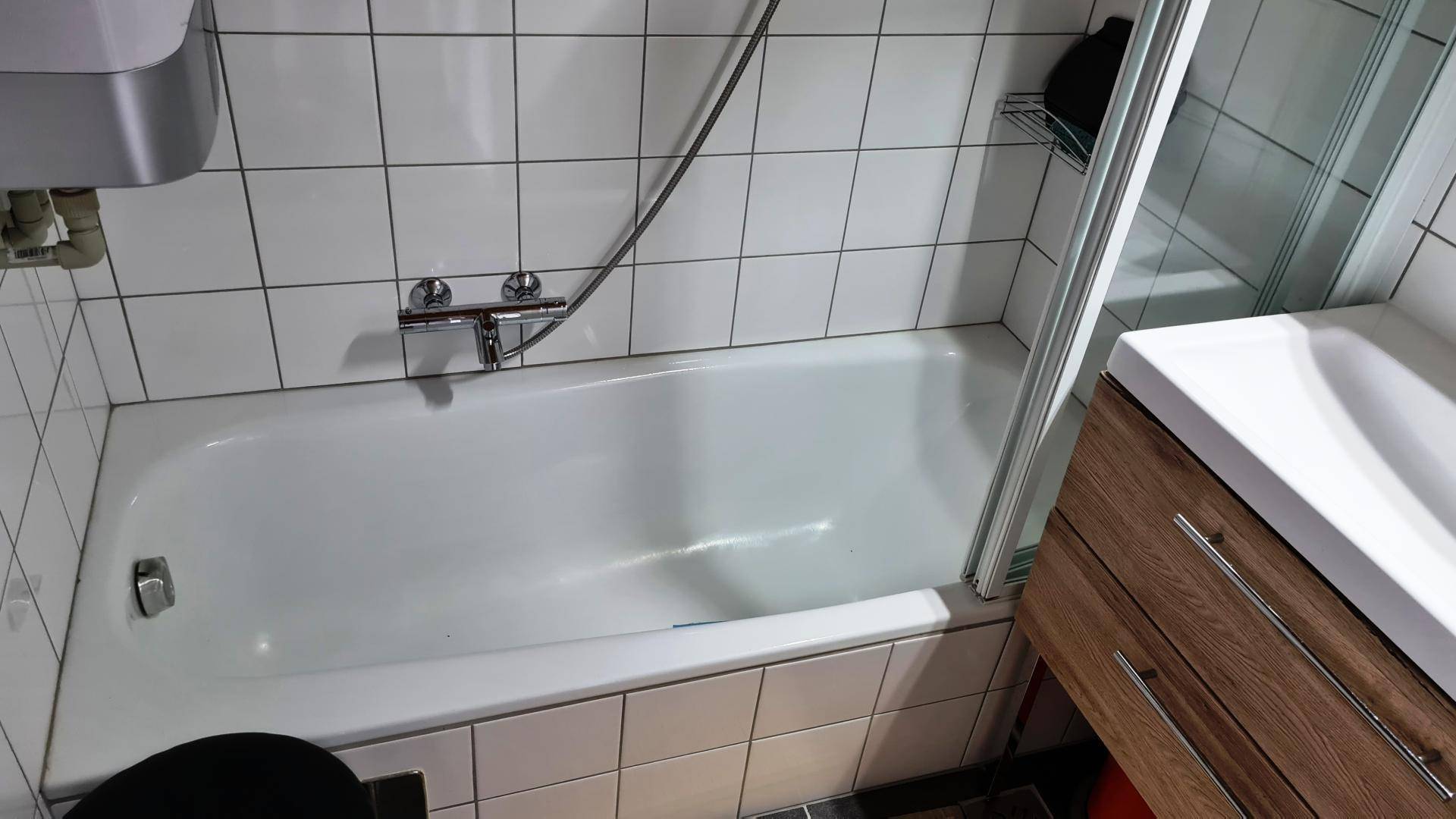 Badezimmer mit Badewanne, Duschabtrennung und Waschbeckenunterschrank.