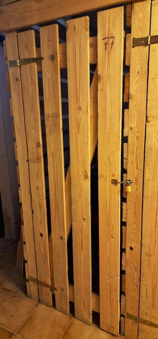 Abgetrennter Lagerraum mit Holzlattenwänden und Fliesenboden.