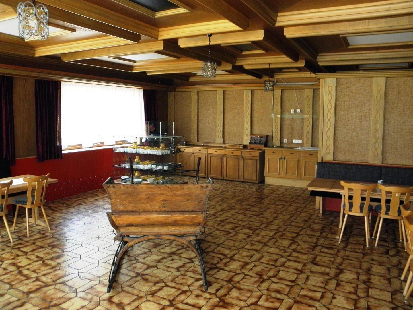 Traditioneller Speisesaal mit Holzwänden, gefliestem Boden und einer Theke mit eingebauten Schränken.