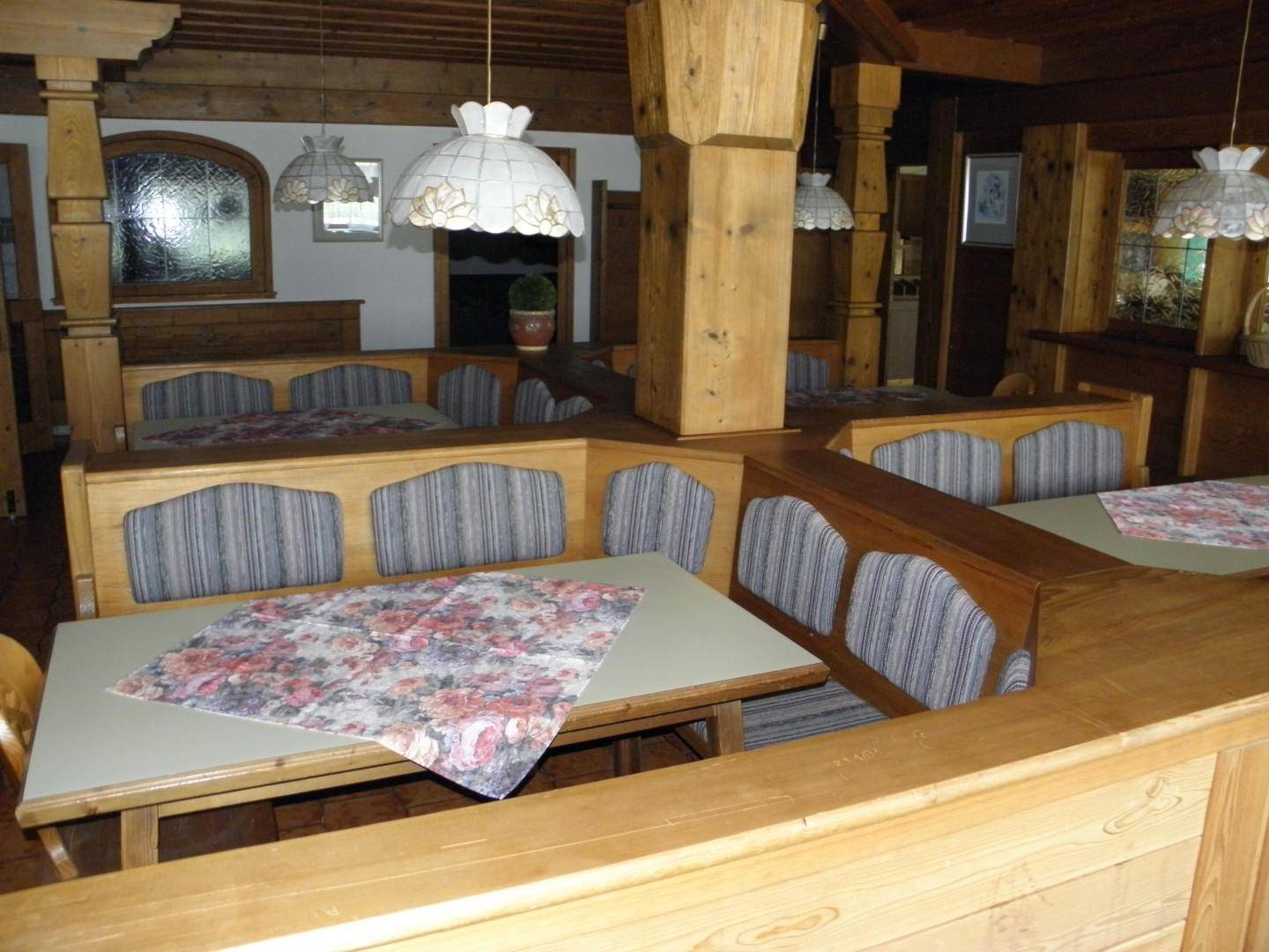 Geräumiger Essbereich im alpinen Stil mit Holzbänken, Tischen und traditionellen Deckenlampen.