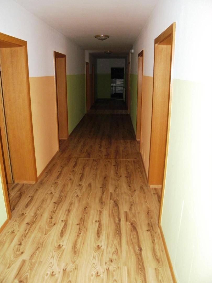 Langer Flur mit Laminatboden und zweifarbigen Wänden, der zu mehreren Zimmern führt.