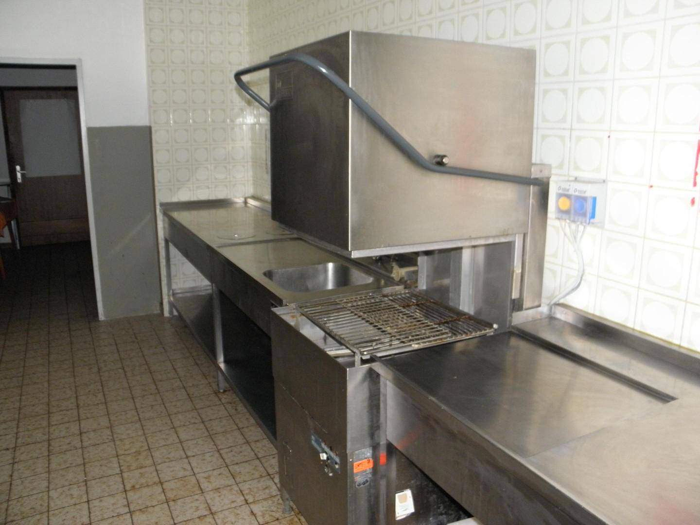 Spülbereich einer professionellen Küche mit Edelstahlbecken und Industriespülmaschine, bereit für den Betrieb.