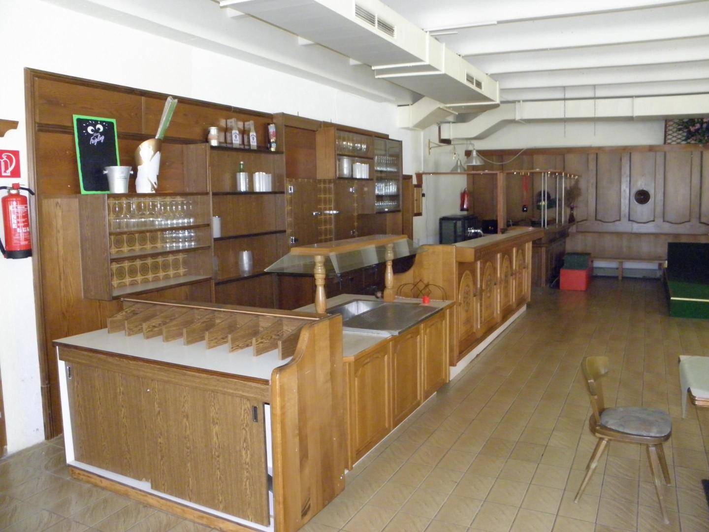 Bar- und Servierbereich in einem großen Saal mit Holzeinrichtung und zahlreichen Gläsern.