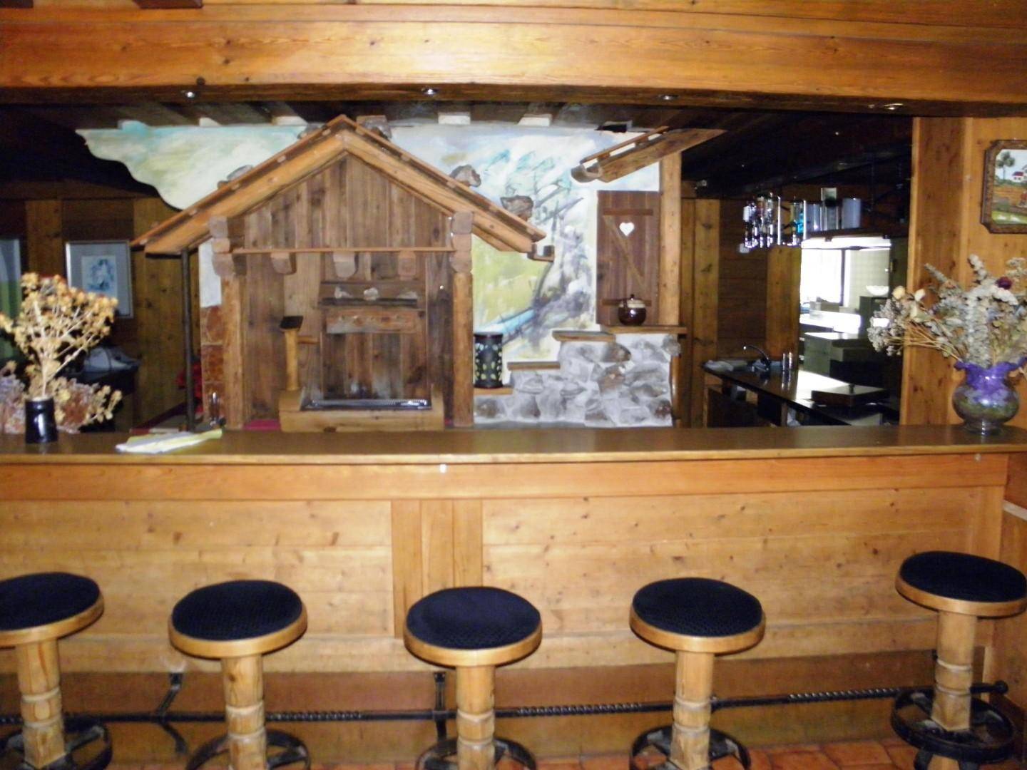 Rustikale Bar im alpinen Stil mit Holztheke und Hockern, dekoriert mit traditionellen Elementen.