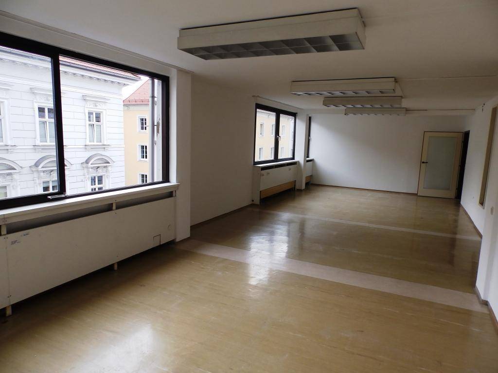 Großer, heller Büroraum mit mehreren Fenstern und Blick auf die umliegenden Gebäude.