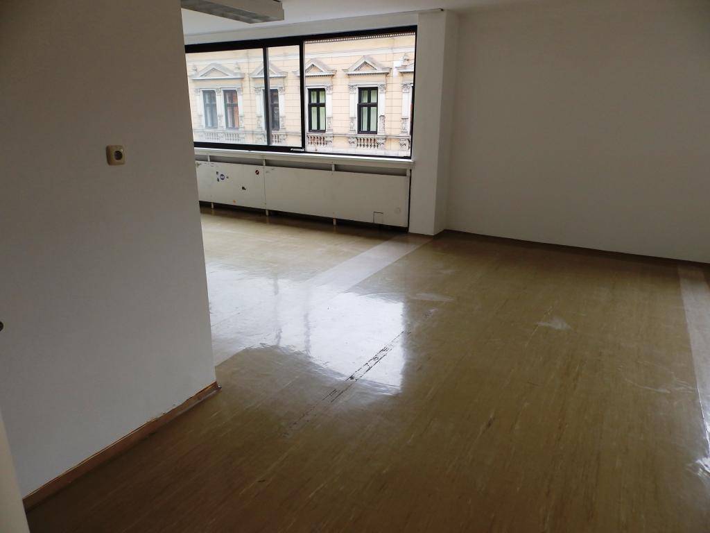 Geräumiger Bürobereich mit großen Fenstern und Blick auf die gegenüberliegenden Gebäude.