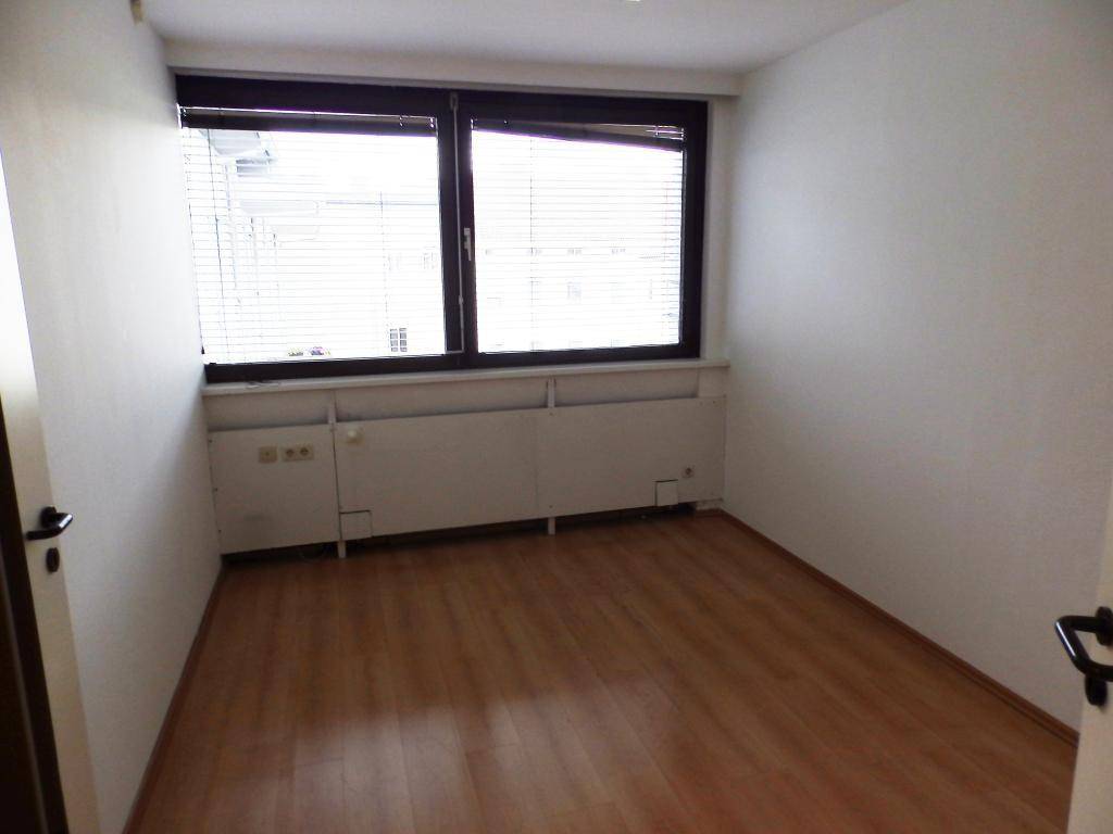 Kleiner Büroraum mit Fenster und Jalousien, ausgestattet mit hellem Laminatboden.