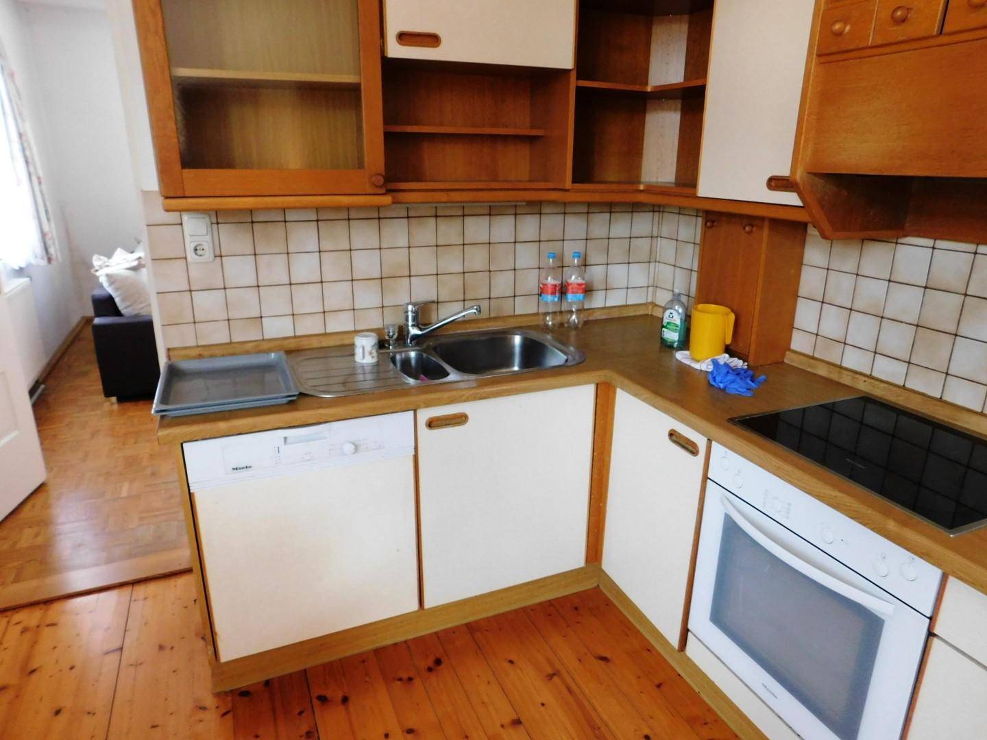Gemütliche Küche mit Holzfronten, Spülbecken und Geschirrspüler, verbunden mit einem angrenzenden Wohnbereich.