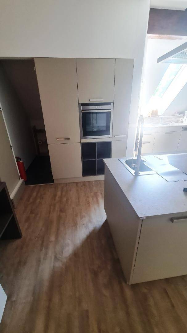 Moderne Einbauküche mit integriertem Backofen und Kücheninsel, in hellem Design gehalten.