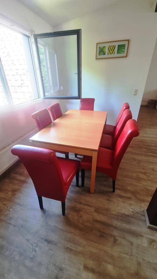 Heller Essbereich mit Holztisch und roten Stühlen, direkt am Fenster für viel Tageslicht.