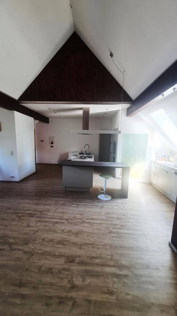 Weitläufiger offener Wohn- und Essbereich mit moderner Küche, Holzbalken und viel Tageslicht.