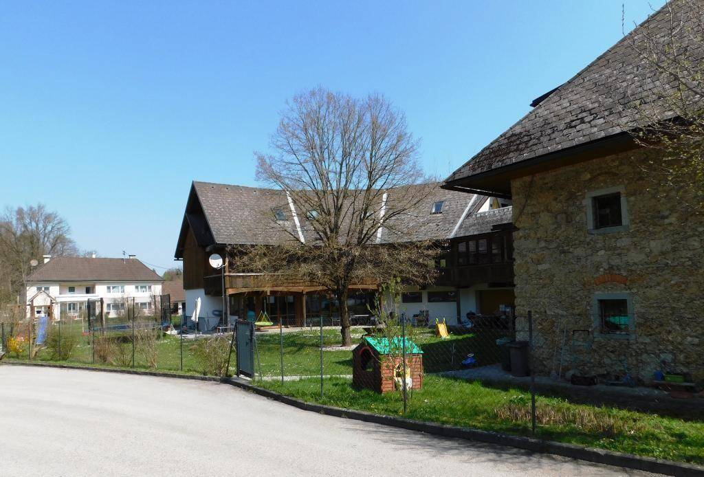 Ansicht des Anwesens von der Straße, mit Haupthaus und Nebengebäude, umgeben von Natur.