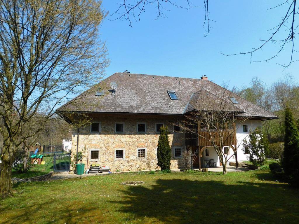 Idyllischer Garten mit weitläufiger Rasenfläche und Blick auf das charmante Gebäude mit Steinfassade.