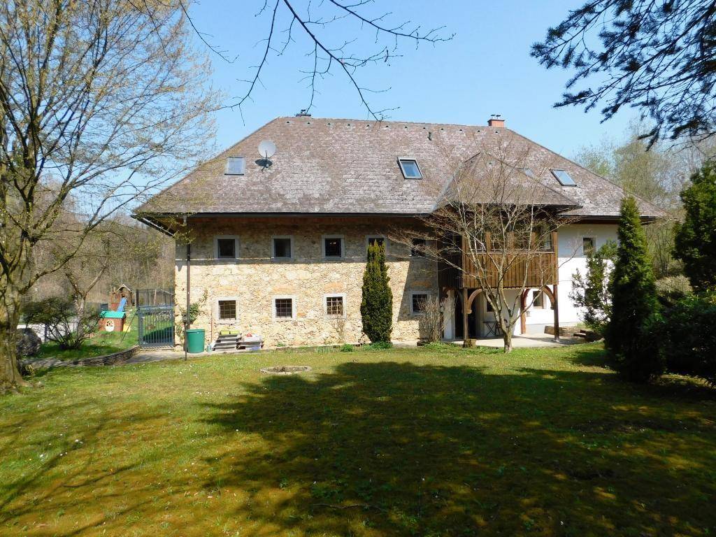 Weitläufiger Gartenbereich mit altem Baumbestand und Blick auf die historische Steinfassade des Hauses.