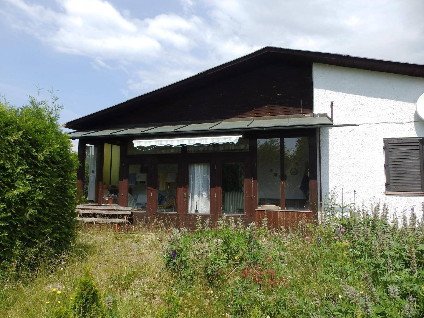 Rückseite des Hauses mit verglastem Wintergarten oder Veranda und einer Markise.